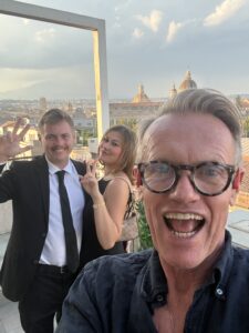 Karl standing in front of an attractive couple.