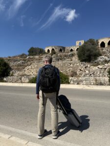 Karl with two pieces of luggage standing on a street.