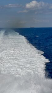 The wake behind a boat in the blue sea.